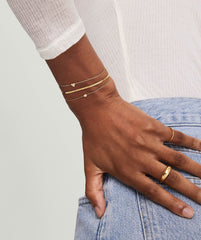 Hand adorned with gold bracelets and rings, featuring the Mini Heart PavÃ© Diamond Bracelet for a playful statement.