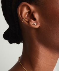 Close-up of a woman's ear wearing Mini Heart PavÃ© Diamond Stud Earrings, handcrafted in 14k solid gold, showcasing their intricate and playful design.