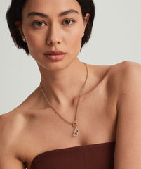 Woman with short dark hair wearing a 14k gold necklace featuring a Lab Grown Diamond Oversized Letter Charm.