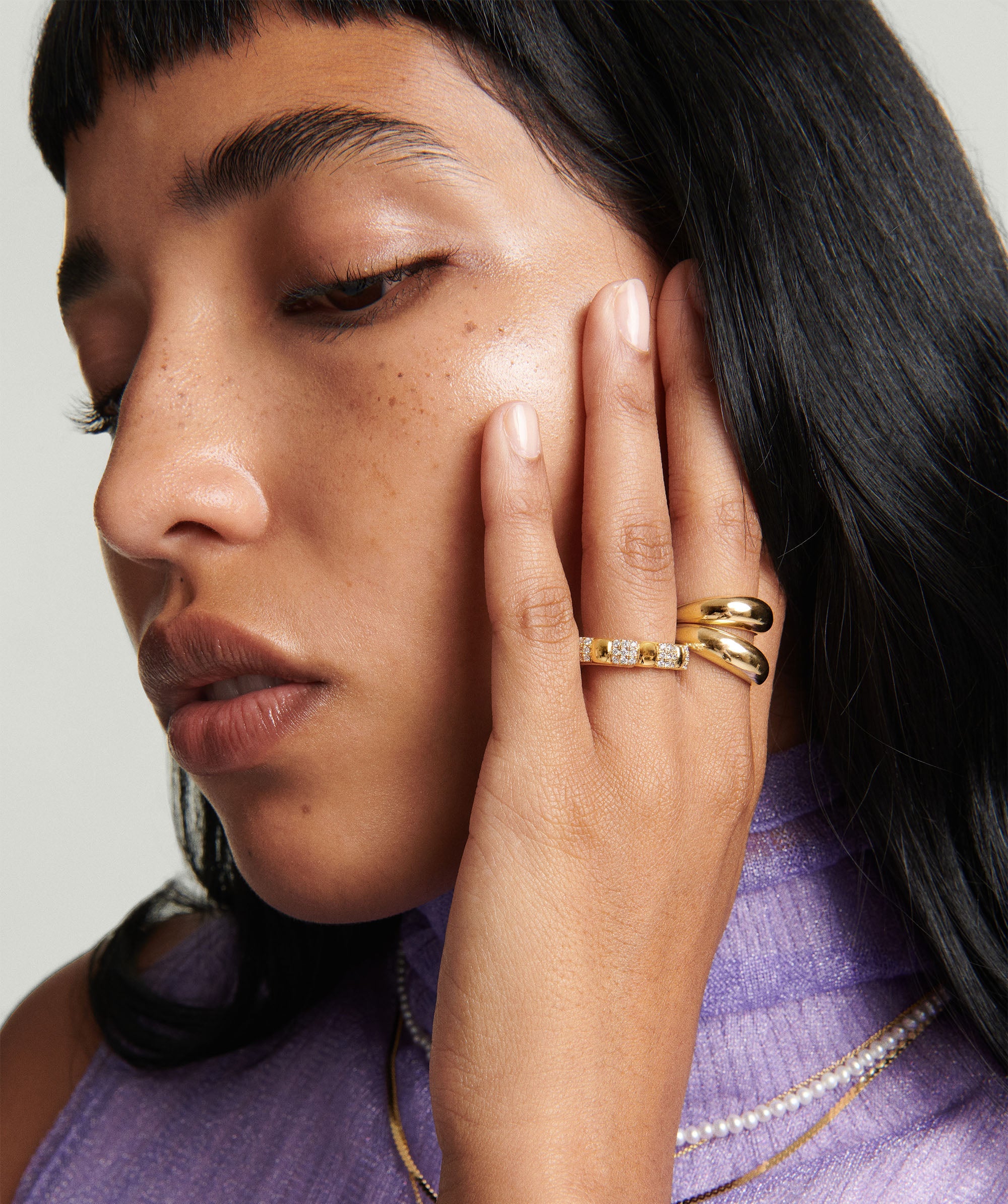 Woman wearing the Thin DÃ´me Ring, a handcrafted 14k gold ring, with her hand gently touching her face.