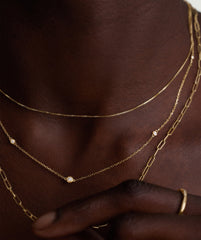 Person wearing the Multi Station Round Diamond Necklace featuring six bezel-set diamonds on a diamond cut cable chain, highlighting its elegant shine and intricate design.