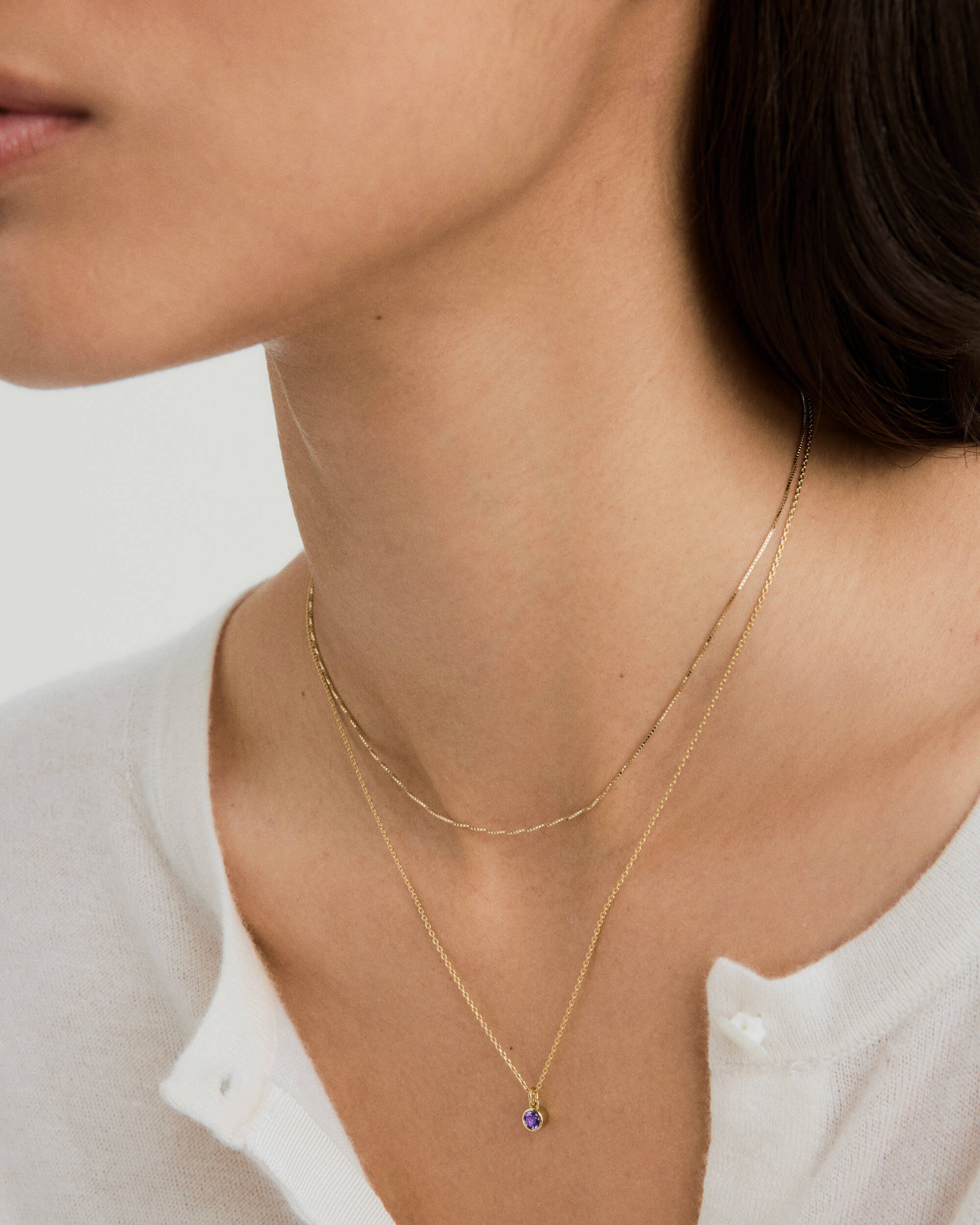 Woman wearing the Sia Birthstone Pendant Necklace, a classic gemstone on a chain, highlighting personal style and astrological significance.