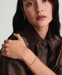 Woman wearing a brown shirt and the Bold Spheres Bracelet, a handcrafted 14k solid gold piece, showcasing a blend of dainty and bold elegance.