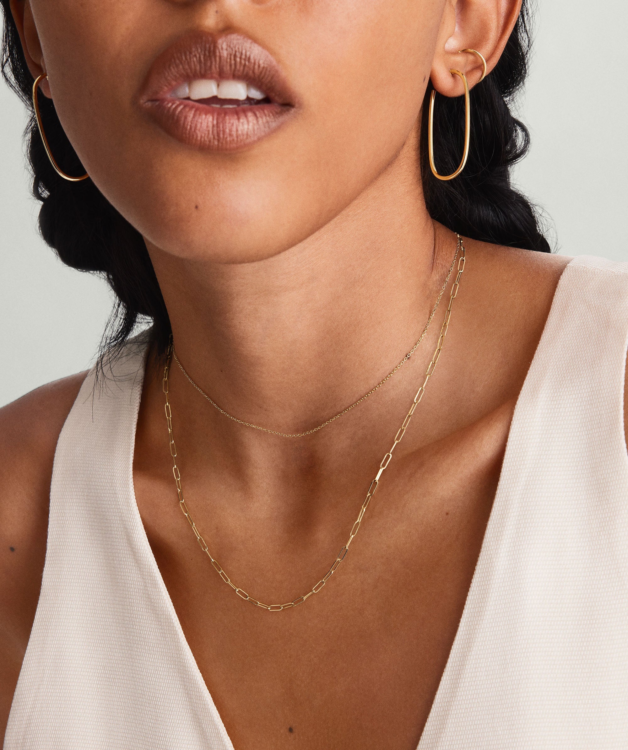 Woman wearing Boyfriend Bold Chain Necklace and gold hoop earrings. Close-up highlights the necklace's raw, bold design, complementing her white shirt.