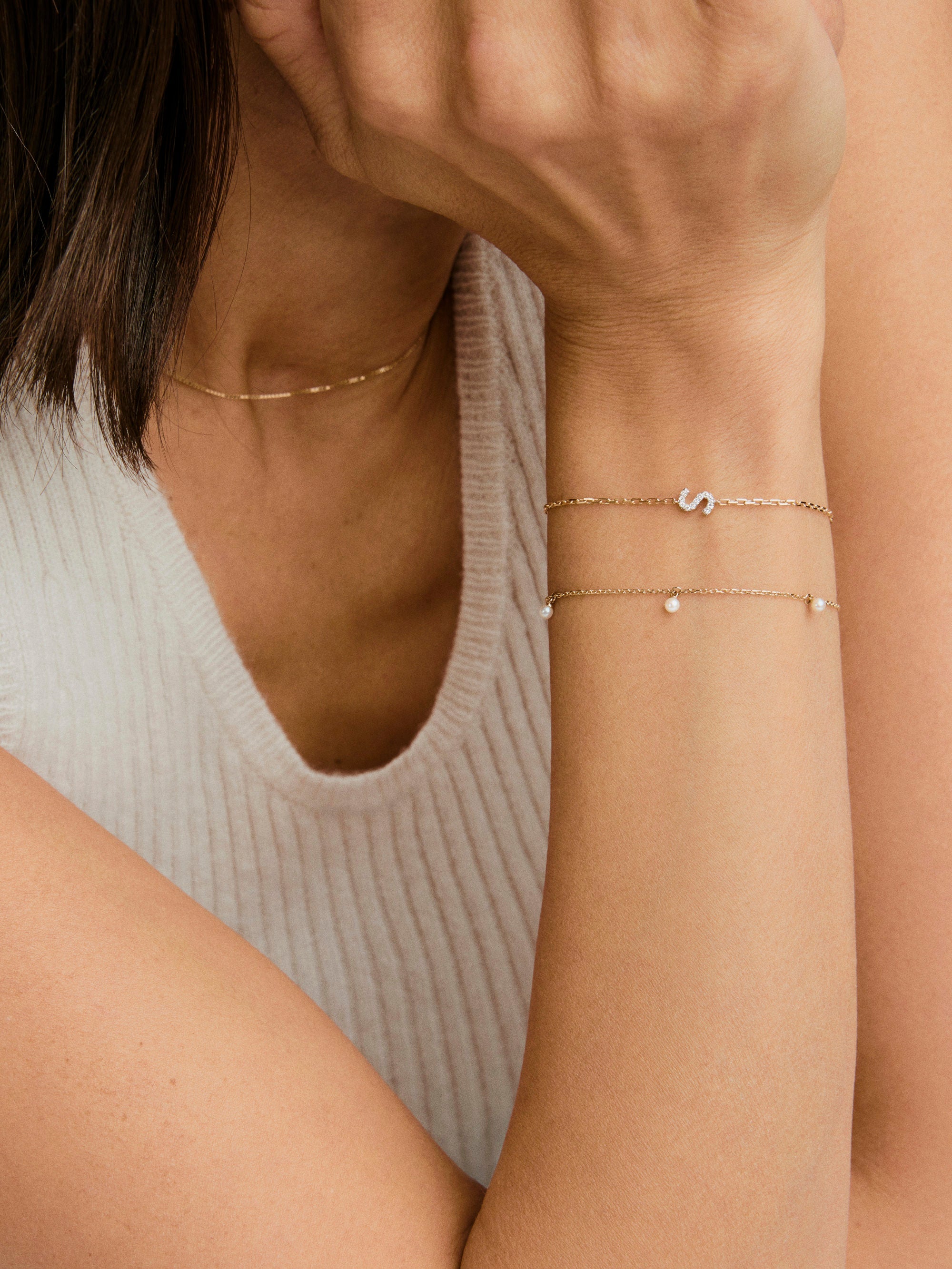 Close-up of a woman wearing the Ama Pearl Bracelet, featuring a delicate gold chain adorned with miniature freshwater pearls, highlighting its elegant design.
