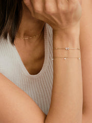 Close-up of a woman wearing the Ama Pearl Bracelet, featuring a delicate gold chain adorned with miniature freshwater pearls, highlighting its elegant design.