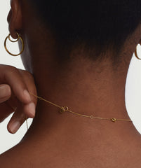 Close-up of a person wearing a gold necklace with a letter charm, showcasing the Chain Double Extender for added length and versatile styling.