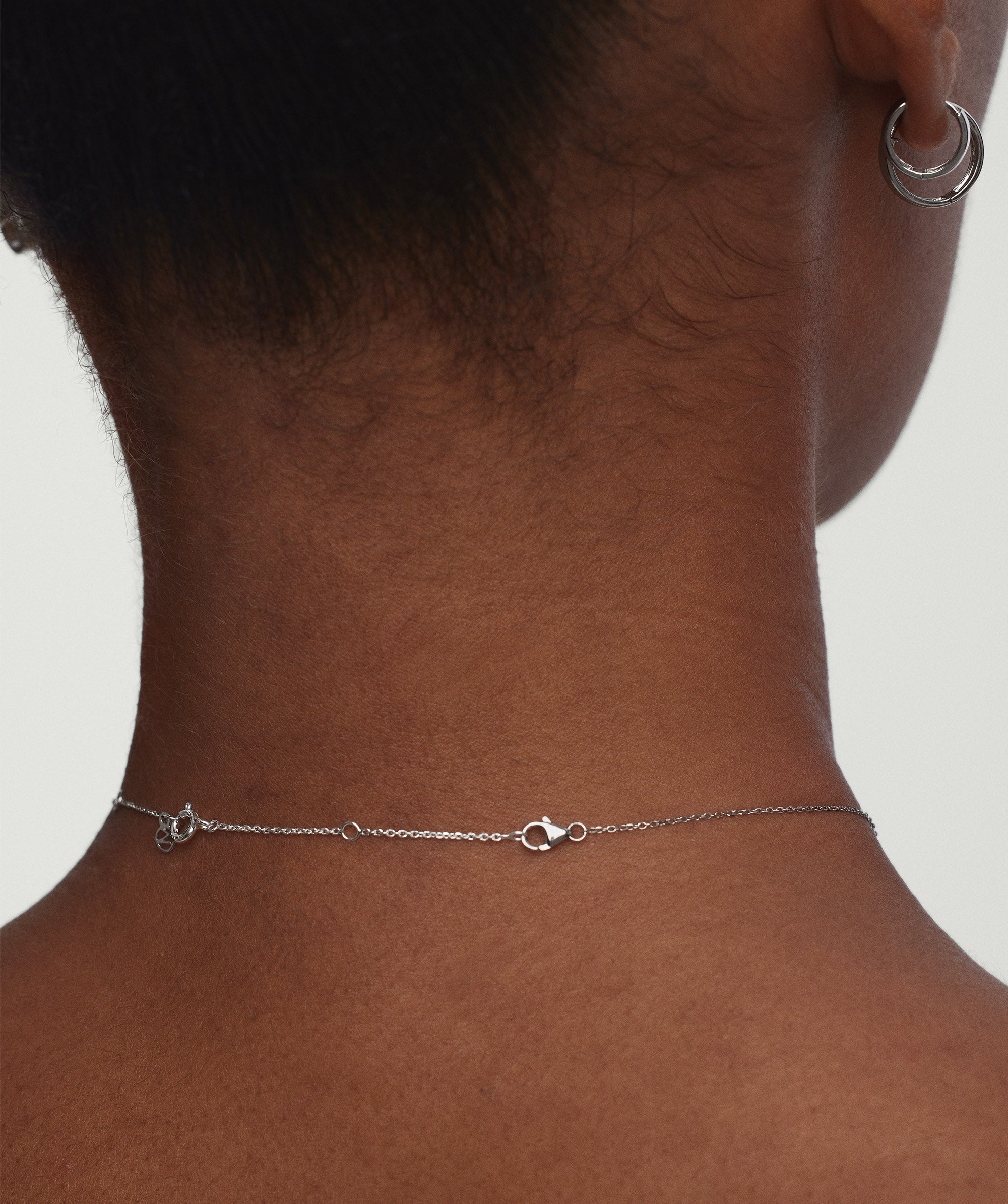 Woman wearing a necklace and earrings, highlighting the Chain Double Extender, shown enhancing the necklace's length for versatile styling options.