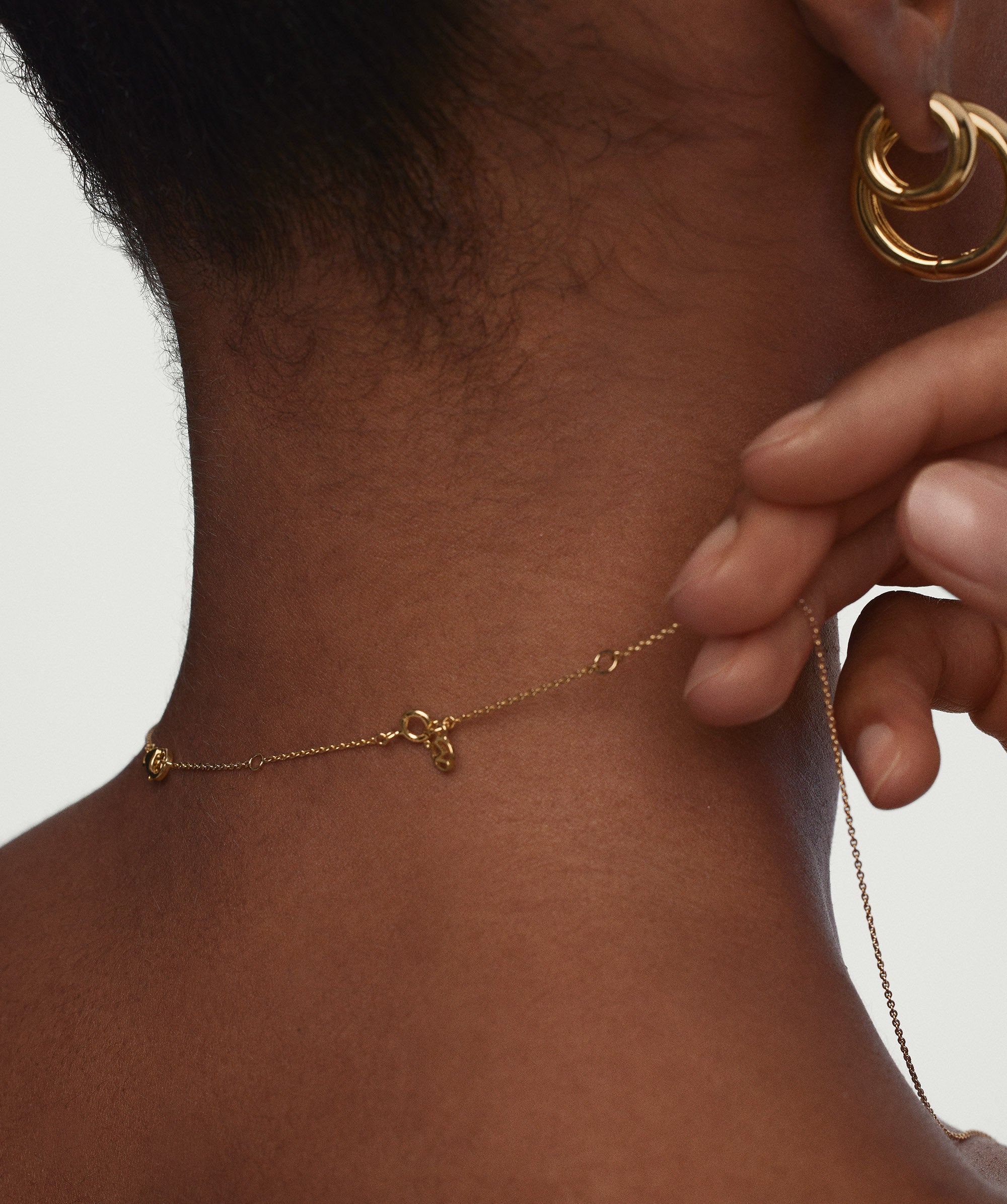 A person wearing a gold necklace and earrings, showcasing the Chain Double Extender for additional length and versatile styling options.