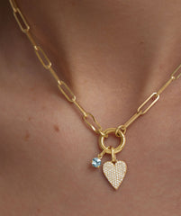 PavÃ© Diamond Heart Pendant on a gold chain with a blue gemstone accent, showcased on a person.