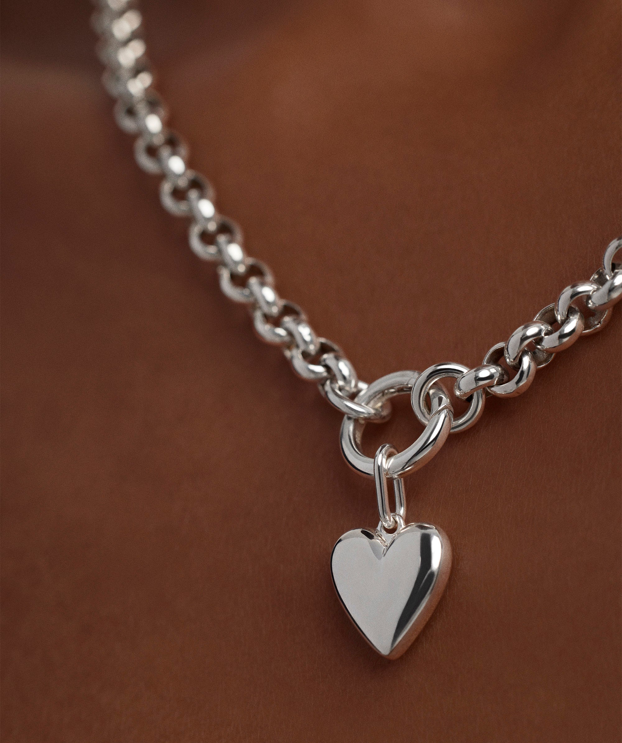 Close-up of a Puffy Heart Charm on a silver chain necklace, showcasing the detailed heart-shaped pendant.