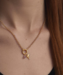 Close-up of a woman wearing a necklace with a gold hummingbird charm pendant, highlighting its elegant design and intricate detail.