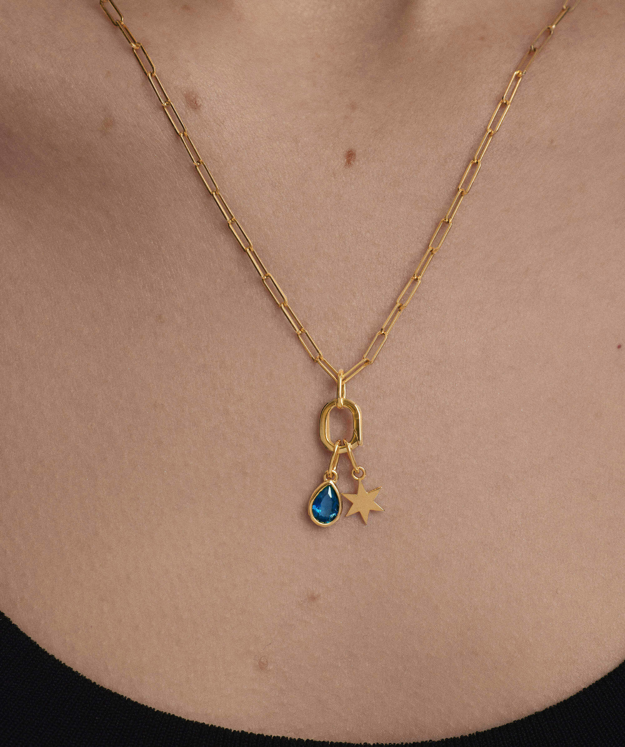 Small Pear Pendant on a gold chain, featuring a blue gem, elegantly worn as a necklace, enhancing everyday style with its unique charm and shine.
