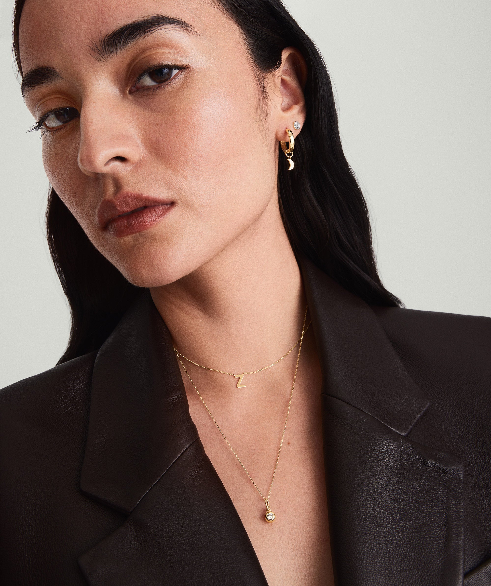 Woman wearing a black jacket and a gold chain necklace, showcasing its potential for layering with other necklaces and chokers.