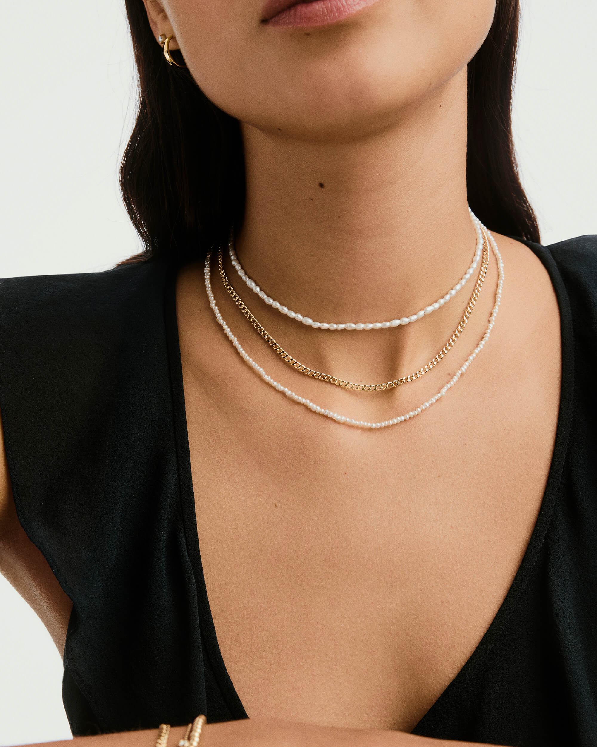 Woman wearing a Curb Chain Necklace, a handcrafted 14k solid gold chain designed for everyday wear, visible around her neck in a close-up shot.