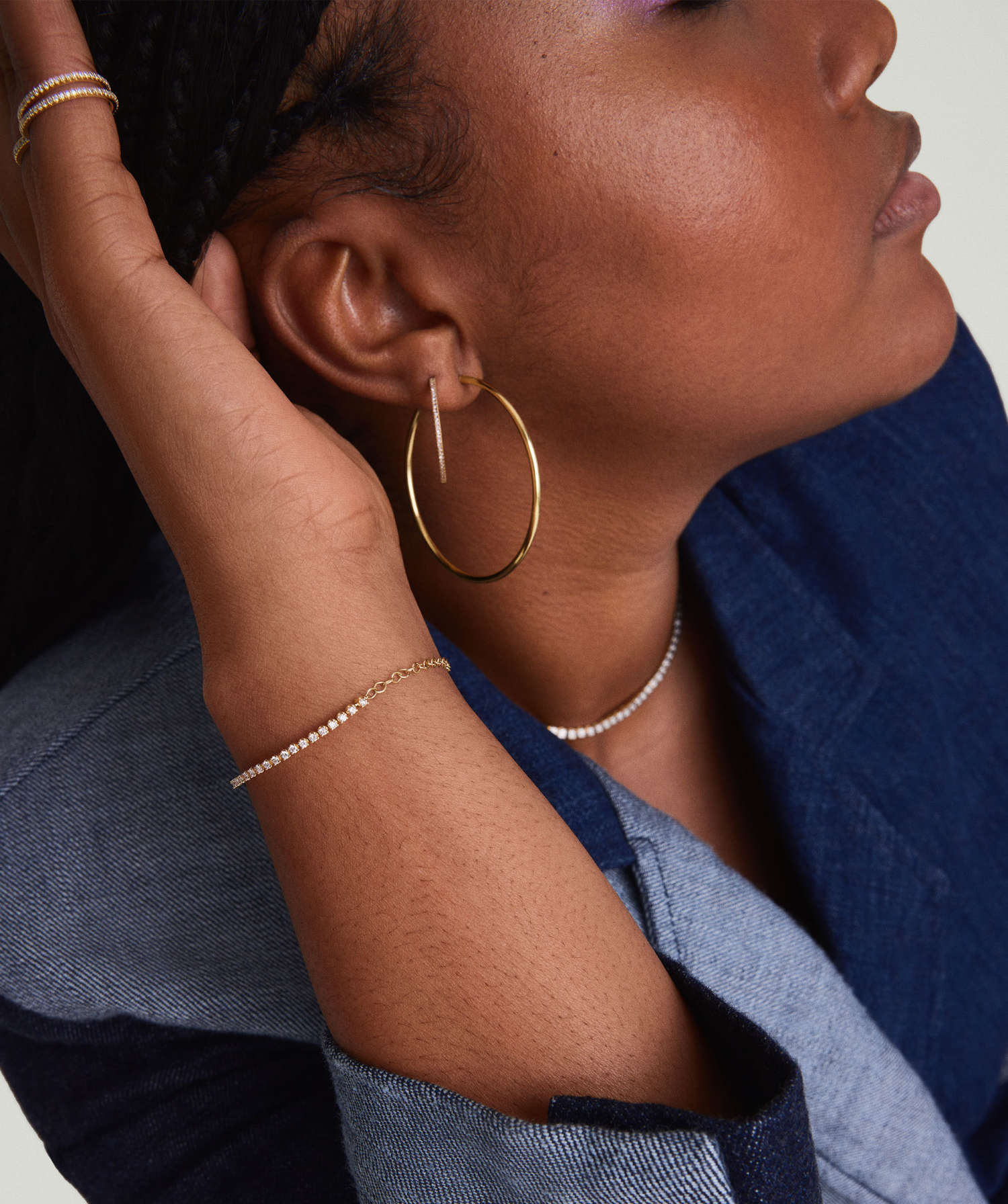 Woman wearing a Diamond Half Tennis Bracelet, handcrafted in 14k solid gold with responsibly sourced diamonds, alongside gold hoop earrings and a beaded necklace.