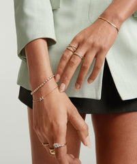 Close-up of a woman's hand showcasing the Diamond Letter Bracelet in 14k gold with pavÃ© diamond-set letters.
