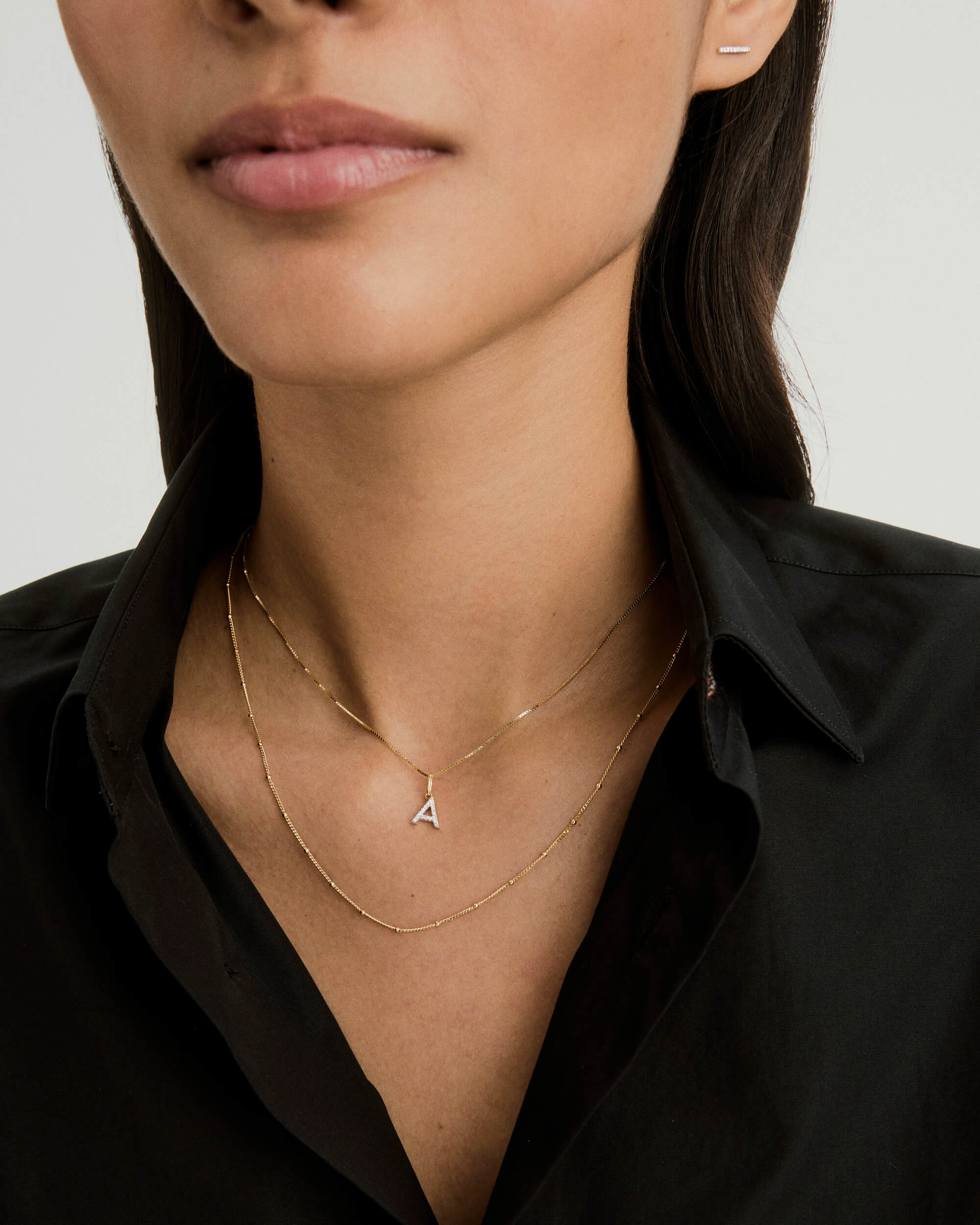 A woman wearing a Diamond Letter Charm necklace, highlighting the charm's elegance. Ideal for pairing with additional chain options, sold separately.