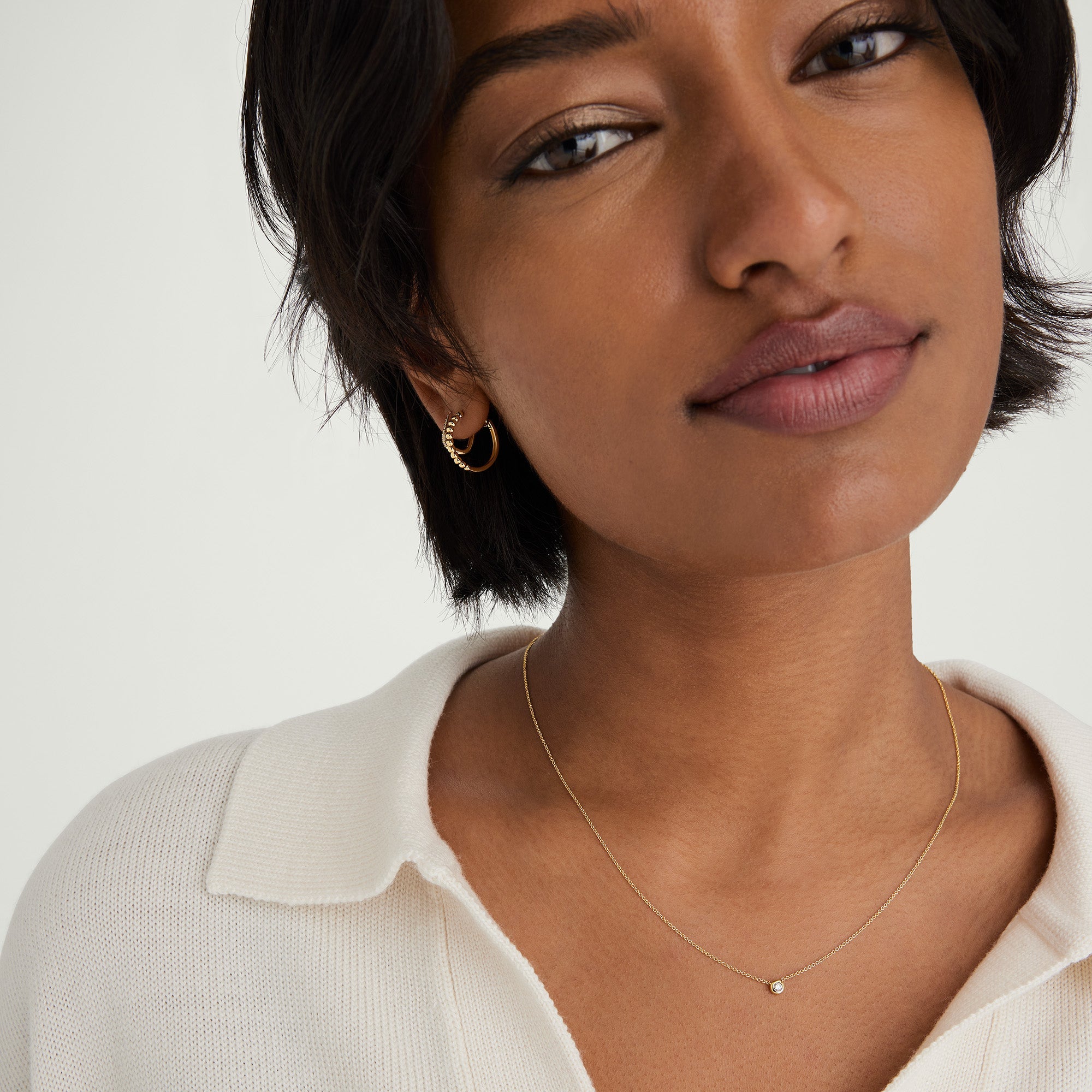 Woman wearing a 14k gold necklace with a bezel-set diamond pendant, showcasing a timeless and elegant design.