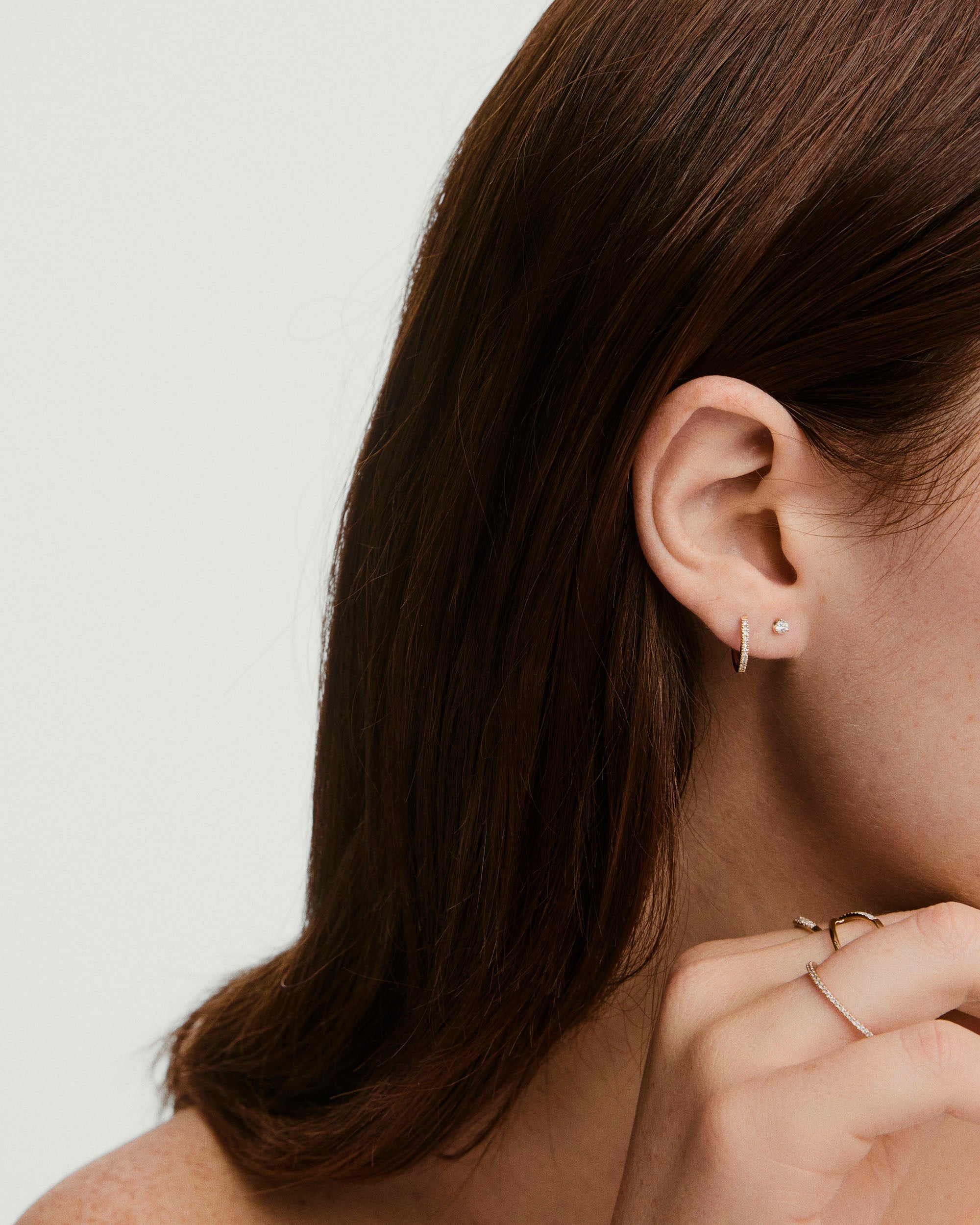 Diamond Mini Stud earring showcased on a woman's ear, emphasizing its prong setting design, ideal for stacking and comfortable wear.