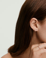 Close-up of a woman's ear wearing the Piercing Studio - Diamond Mini Flat Back Stud, highlighting its 14k gold design and comfortable threadless flat back.