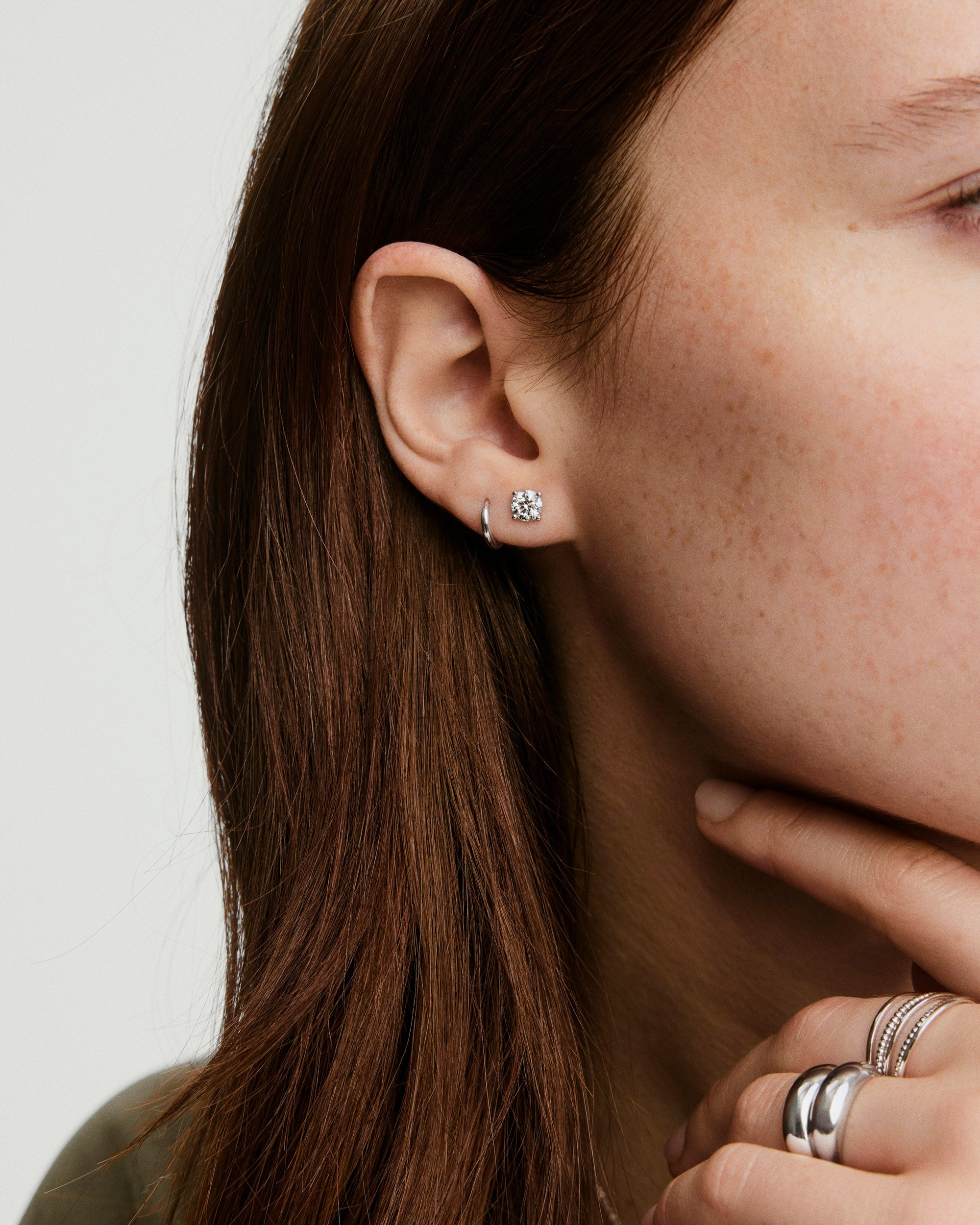 Lab Grown Diamond Round Studs 1 TCW showcased on a woman's ear, highlighting their sparkle and elegance, set in 14k solid gold.