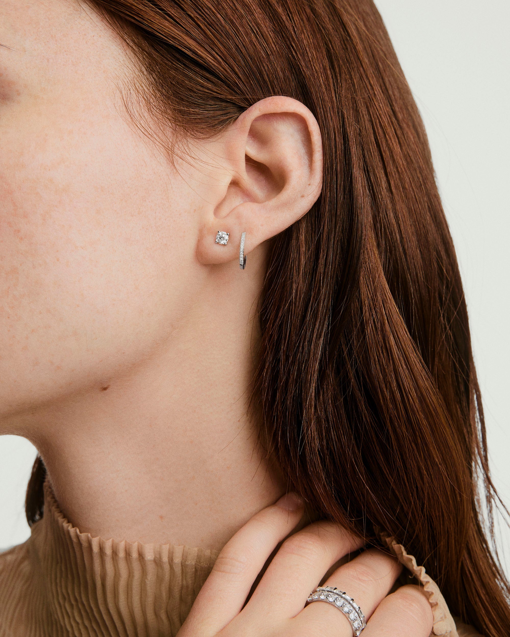 Close-up of a woman's ear adorned with Large Diamond Studs, showcasing a handcrafted, square-cut diamond earring as a prominent fashion accessory.