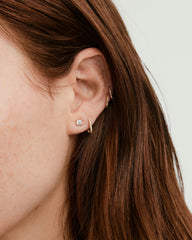 Close-up of a woman's ear adorned with large diamond studs, showcasing a handcrafted, unique diamond setting for timeless elegance.