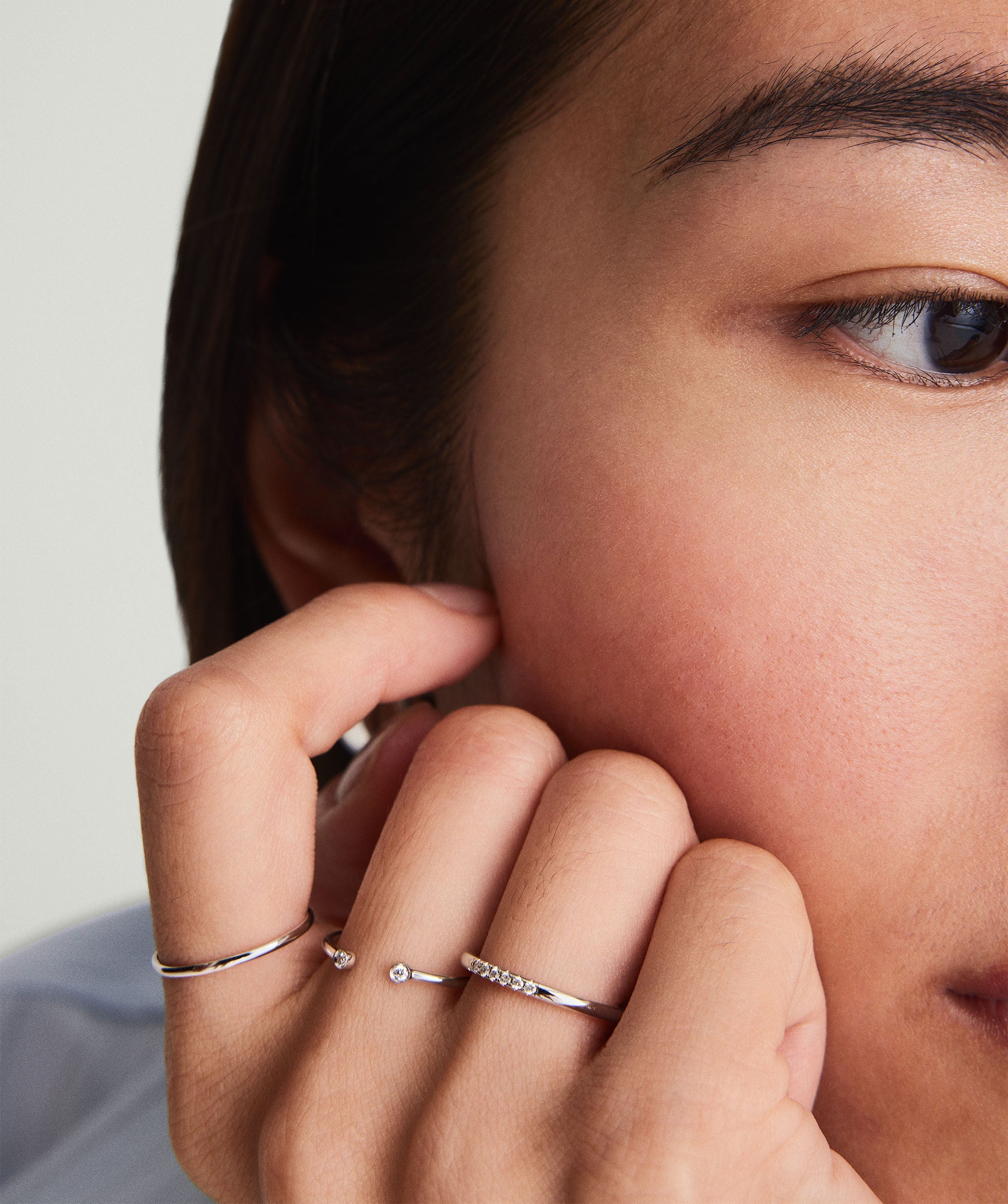 Close-up of a woman's face showcasing a Diamonds Open Ring with bezel-set diamonds on her finger.