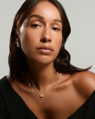 Young woman wearing the Lucia Necklace, featuring a delicate silver chain with a round faceted pendant, paired with matching silver hoop earrings.