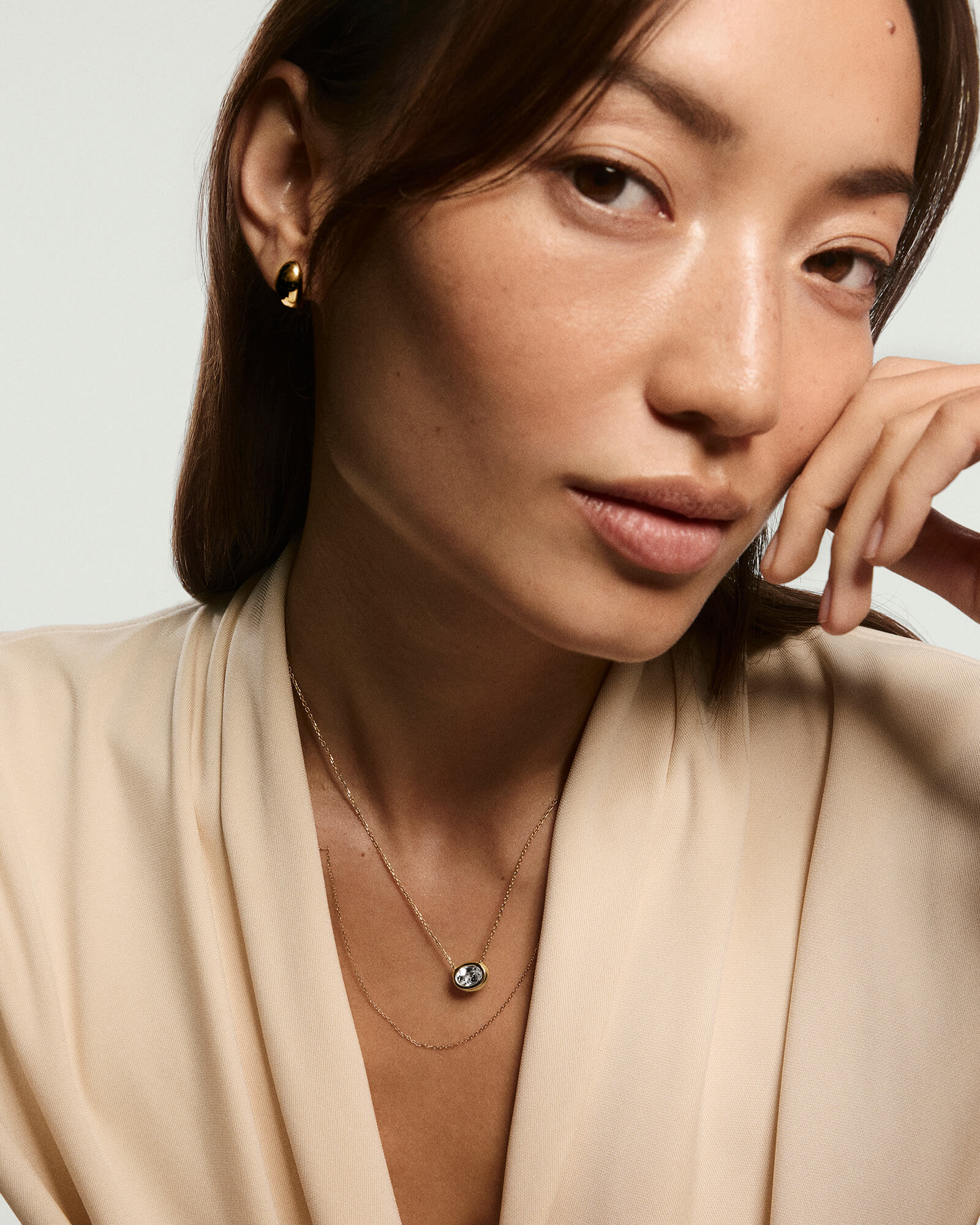 Young woman wearing the Lucia Necklace, showcasing a lab-grown sapphire set in an oval gold bezel on a delicate chain, exuding minimal elegance.