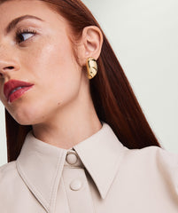Woman wearing Mega DÃ´me Earrings, looking to the side. Focus on her lips, neck, and the bold earrings from the DÃ´me collection.