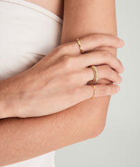 Person wearing the Dot Ring on their finger, shown in a close-up of hands with gold rings, highlighting the ring's stackable design.