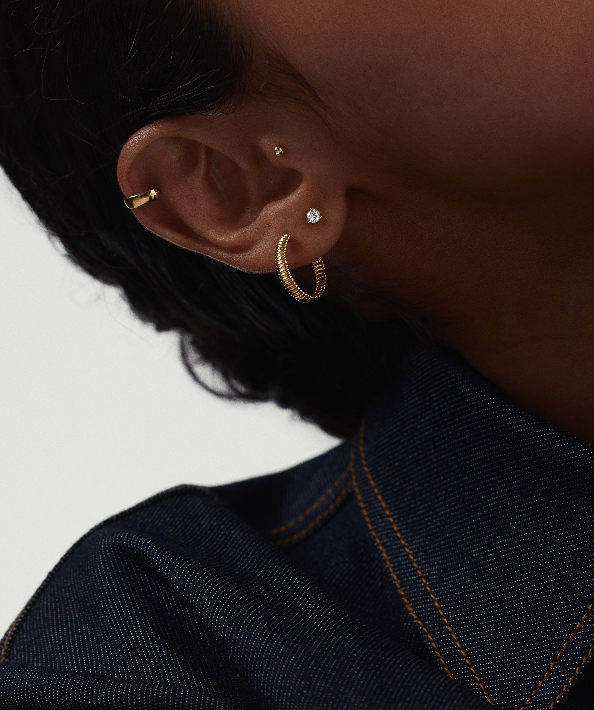 Close-up of a woman's ear featuring the Piercing Studio - Round Diamond Flat Back Stud, highlighting the simple diamond design as a fashionable accessory.