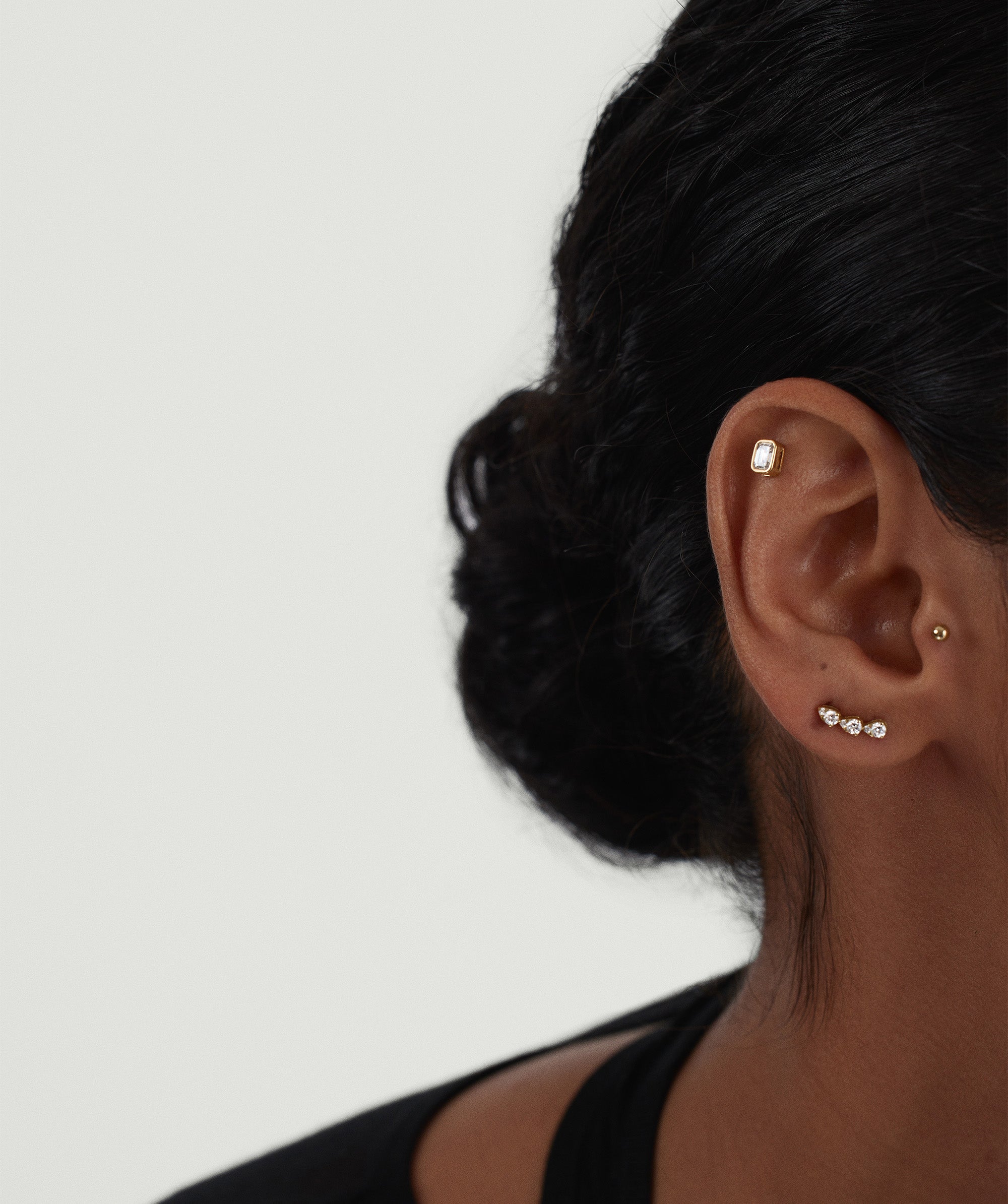 Close-up of a woman's ear wearing Lab Grown Diamond Pear Climber Studs, showcasing a trio of diamonds elegantly climbing along the earlobe.