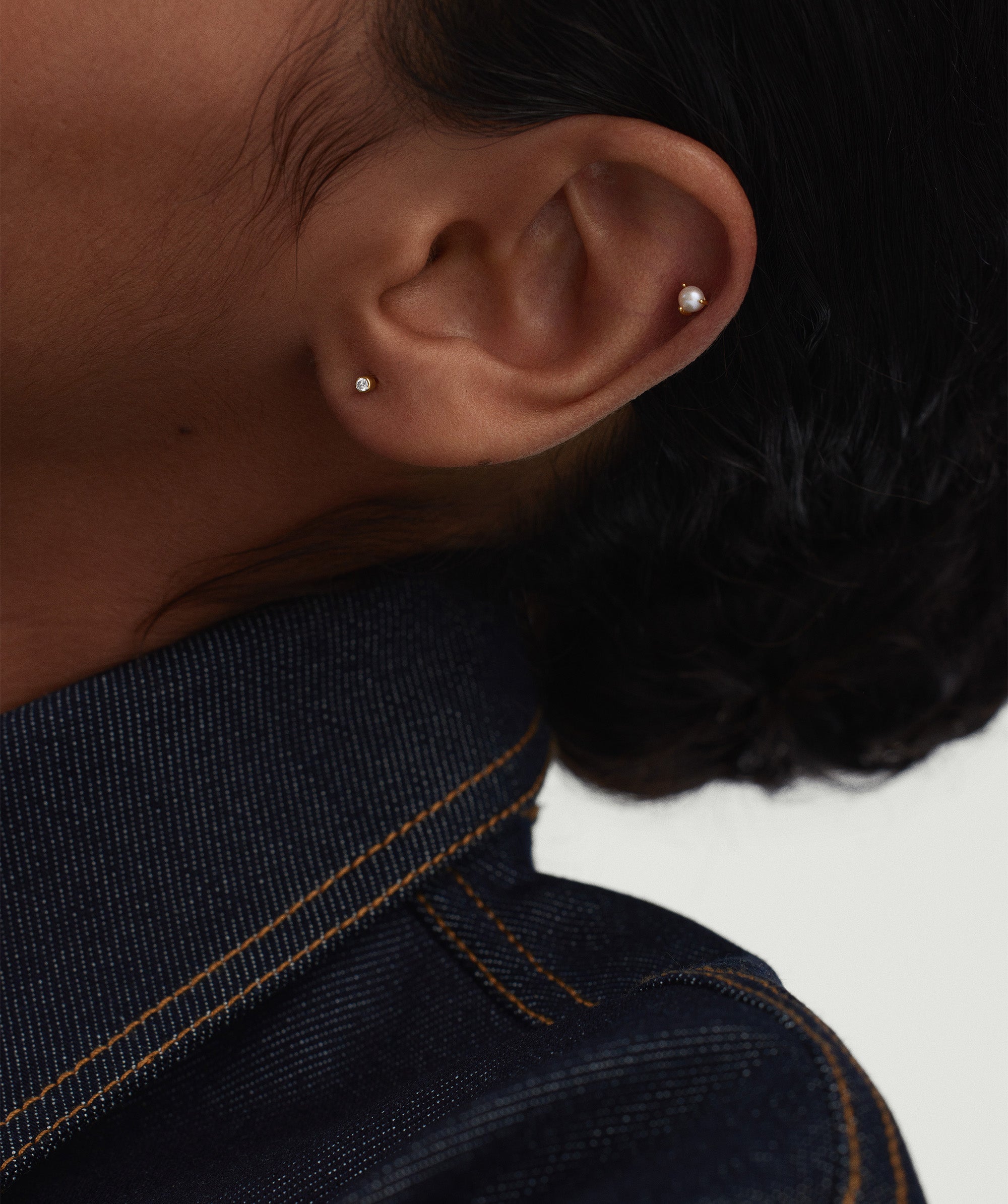 Close-up of a person's ear featuring the Piercing Studio - Micro Diamond Flat Back Stud, showcasing its elegant design and subtle yet impactful presence.