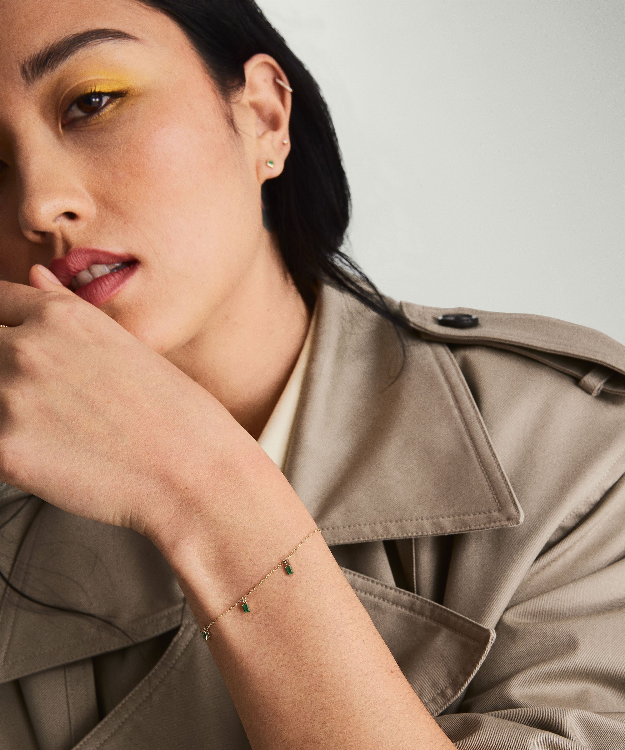 Woman highlighting her Baguette Gemstone Bracelet, hand resting on chin. Close-up showcases the bracelet's intricate details, perfect for stacking.
