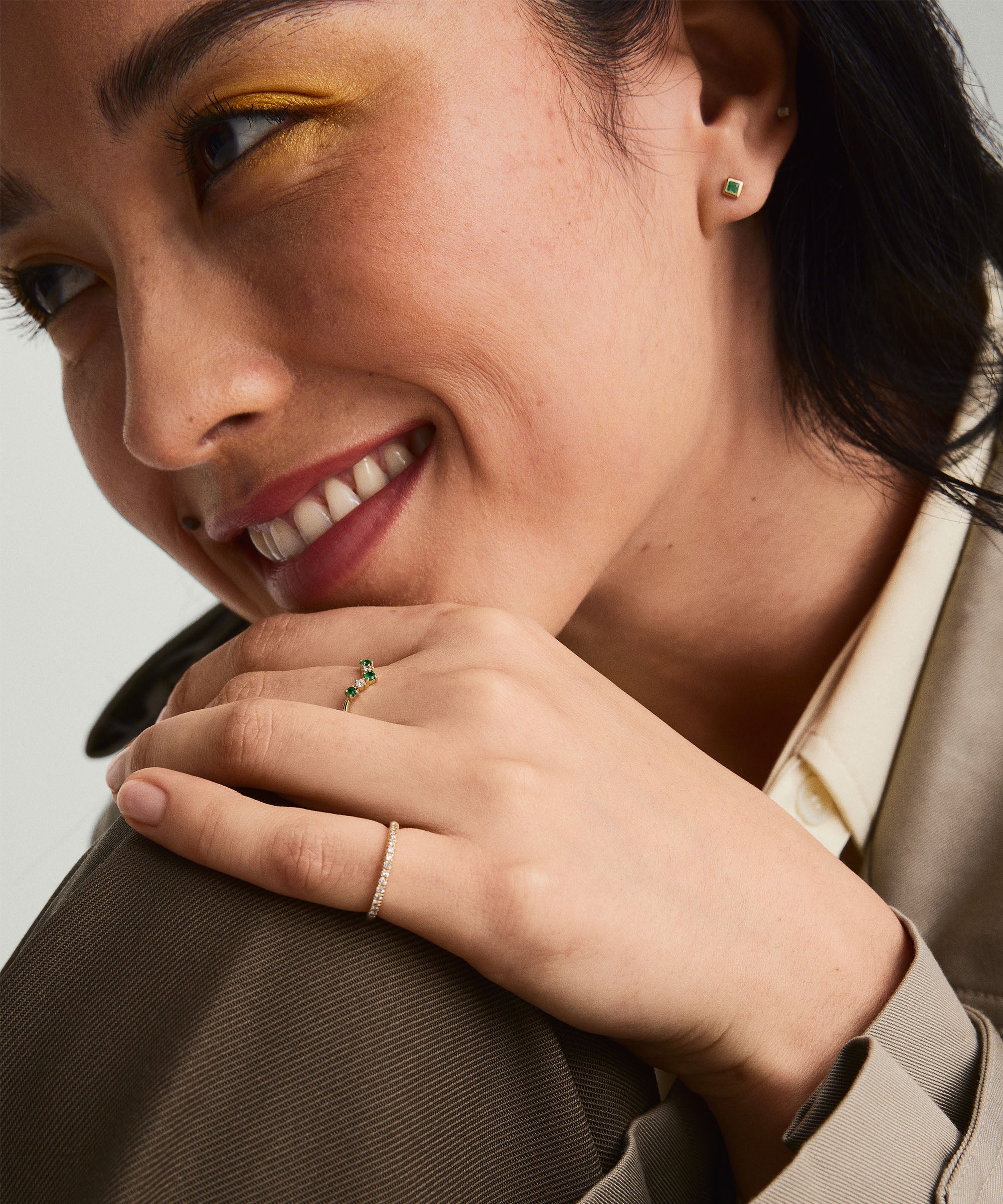 Emerald and Diamond Wishbone Ring worn by smiling woman, showcasing the ring's design with emerald gemstones and diamonds on her finger.