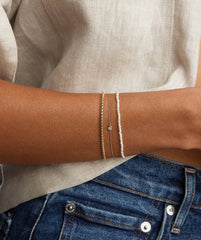 A person wearing a Micro Pearl Bracelet, handcrafted in 14k gold with freshwater pearls, showcased on their wrist for an elegant look.