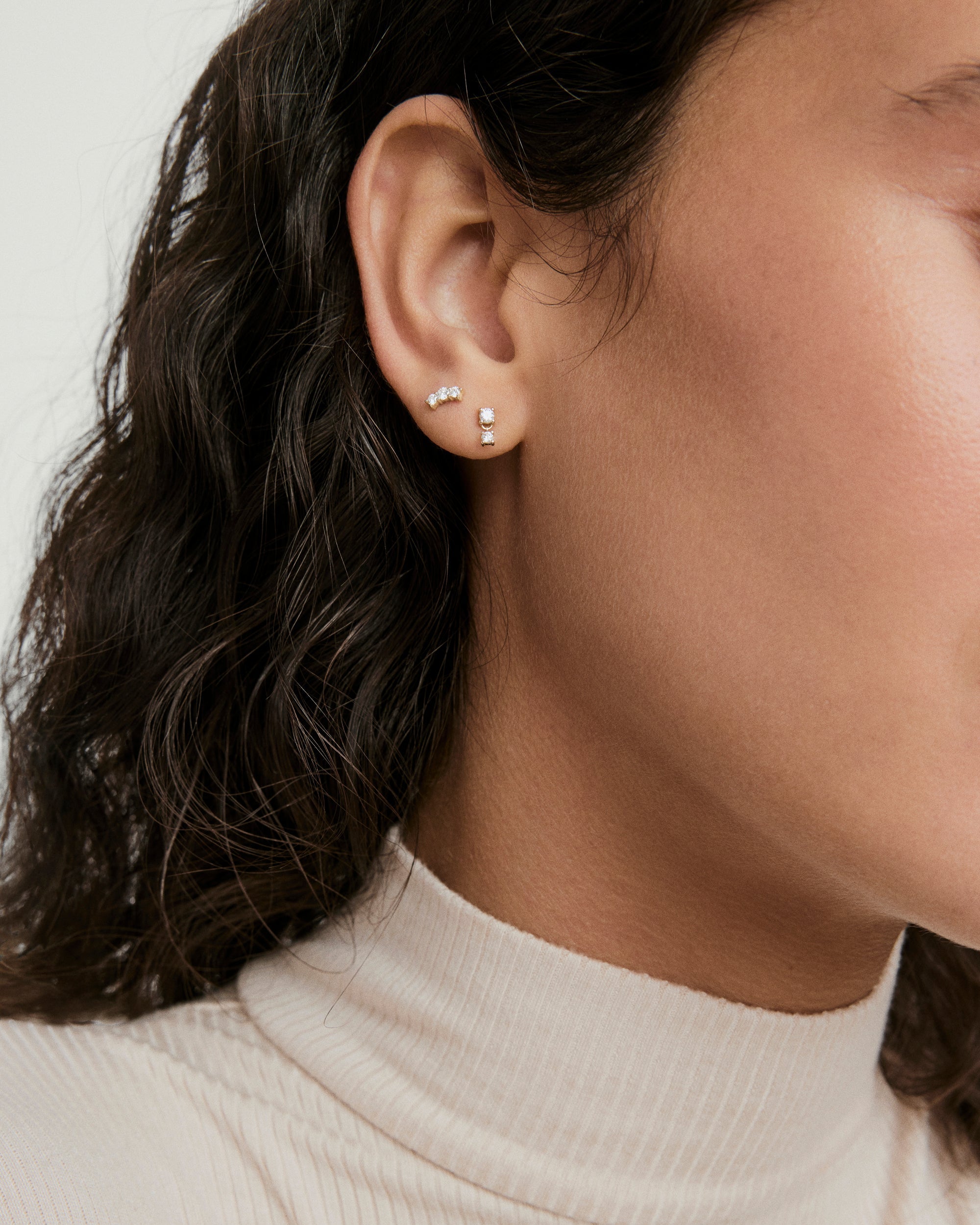 Droplet Stud earring close-up on woman's ear, featuring a diamond stud with a dangling charm resembling a water droplet, designed for comfortable all-day wear.