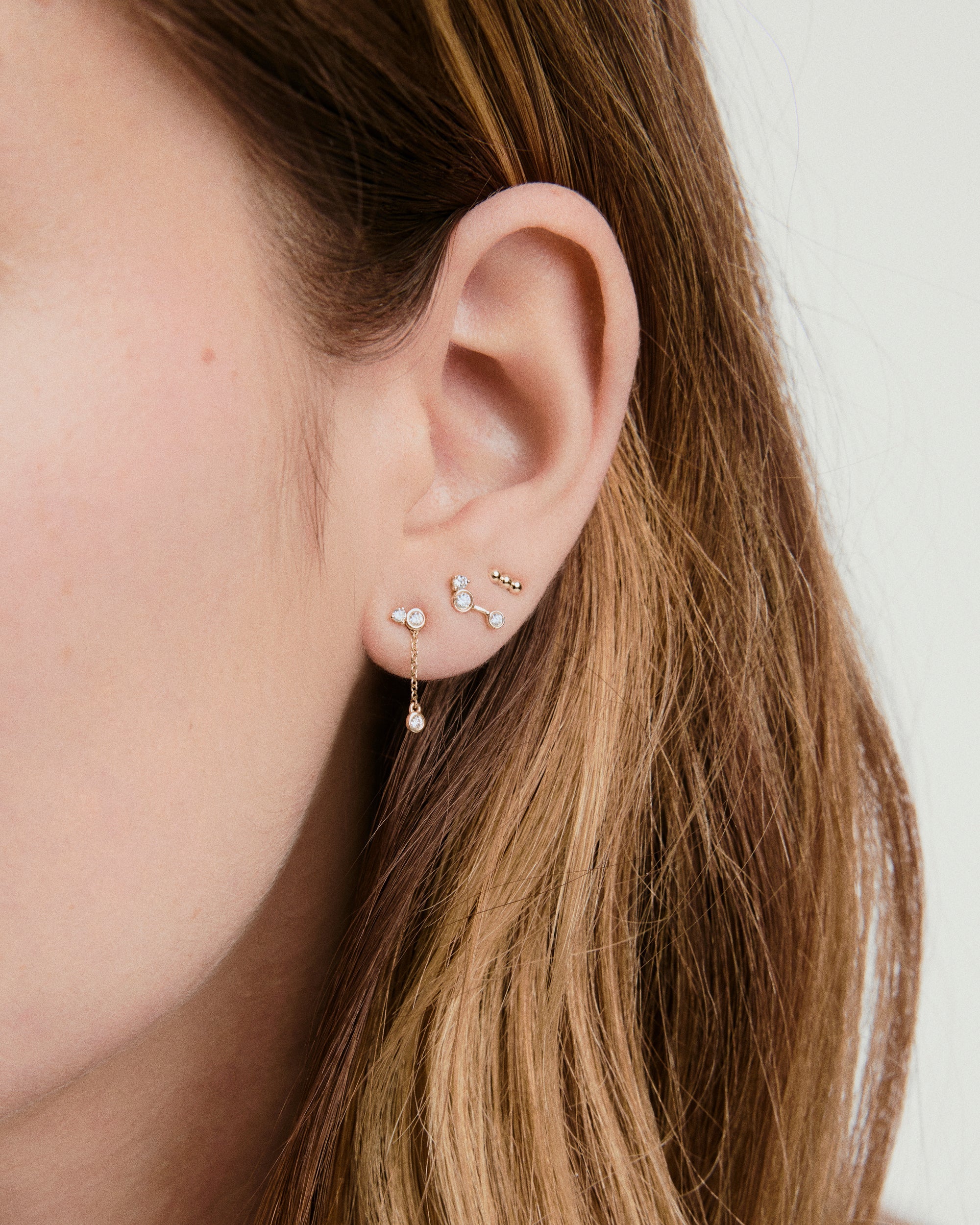 Celeste Lab Grown Diamond Chain Stud on a woman's ear, showcasing clustered diamonds and a dangling drop chain, inspired by night sky constellations.