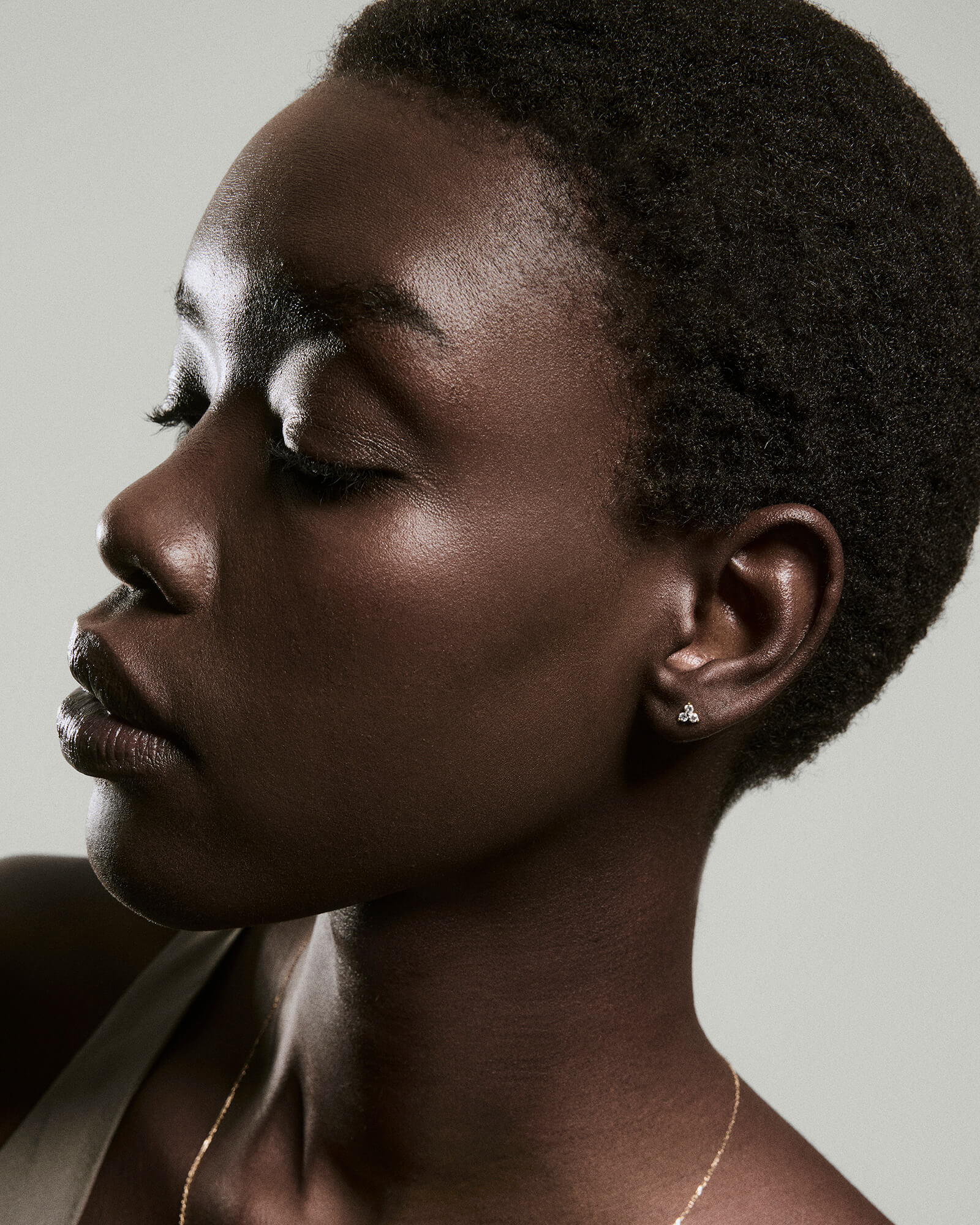 Profile of a person wearing Diamond Lotus Flat Back Stud earrings, featuring three bright diamonds in a triangular cluster, set in 14k solid gold.