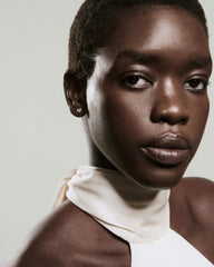 Side view of a person wearing Lab Grown Diamond Petal Drops, with triple-diamond studs adding a subtle edge to their minimalist off-white halter top.