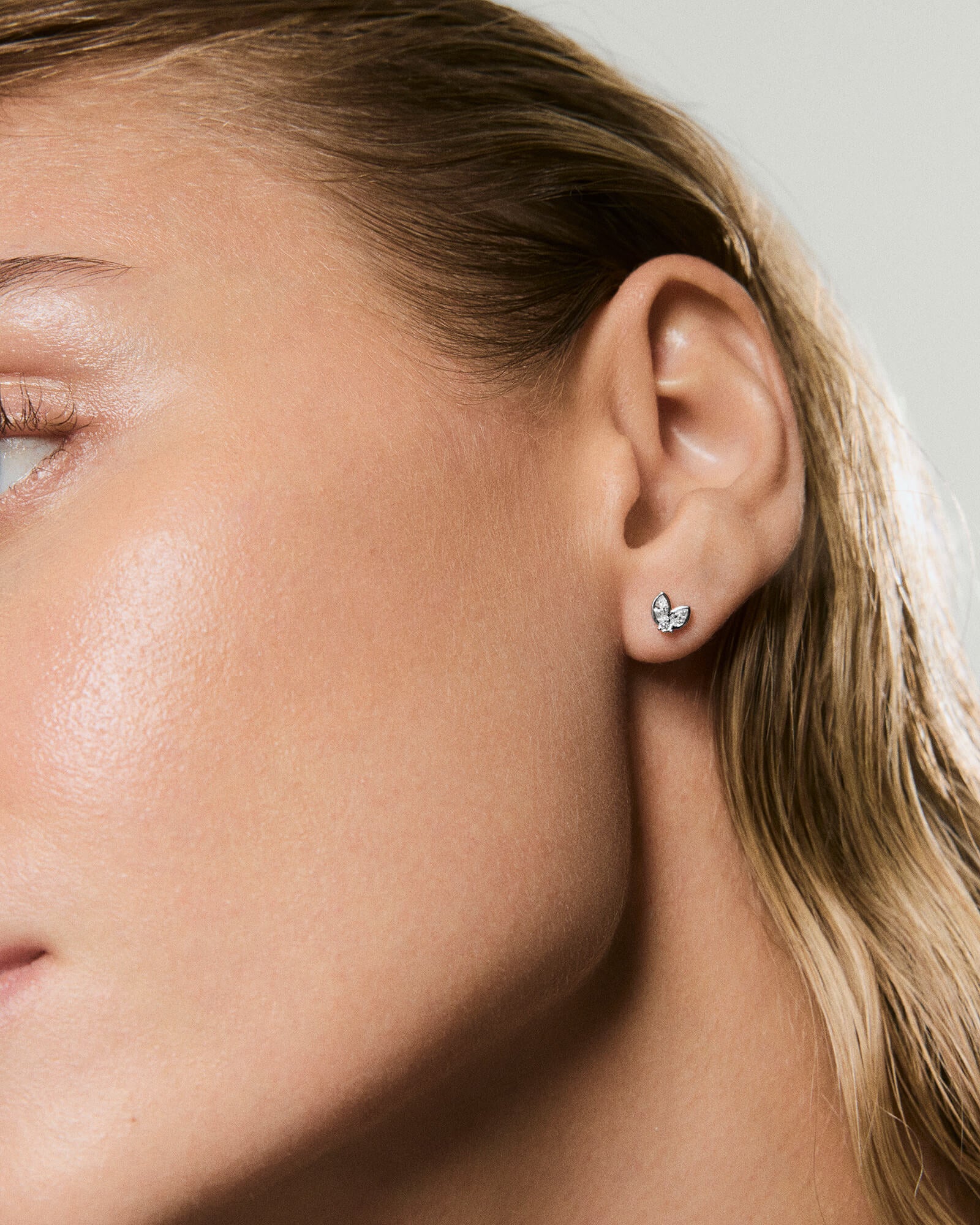 Close-up of a woman's ear wearing Piercing Studio - Lab Grown Diamond Petal Stud, featuring a cluster of marquise and round-cut stones in a floral motif.