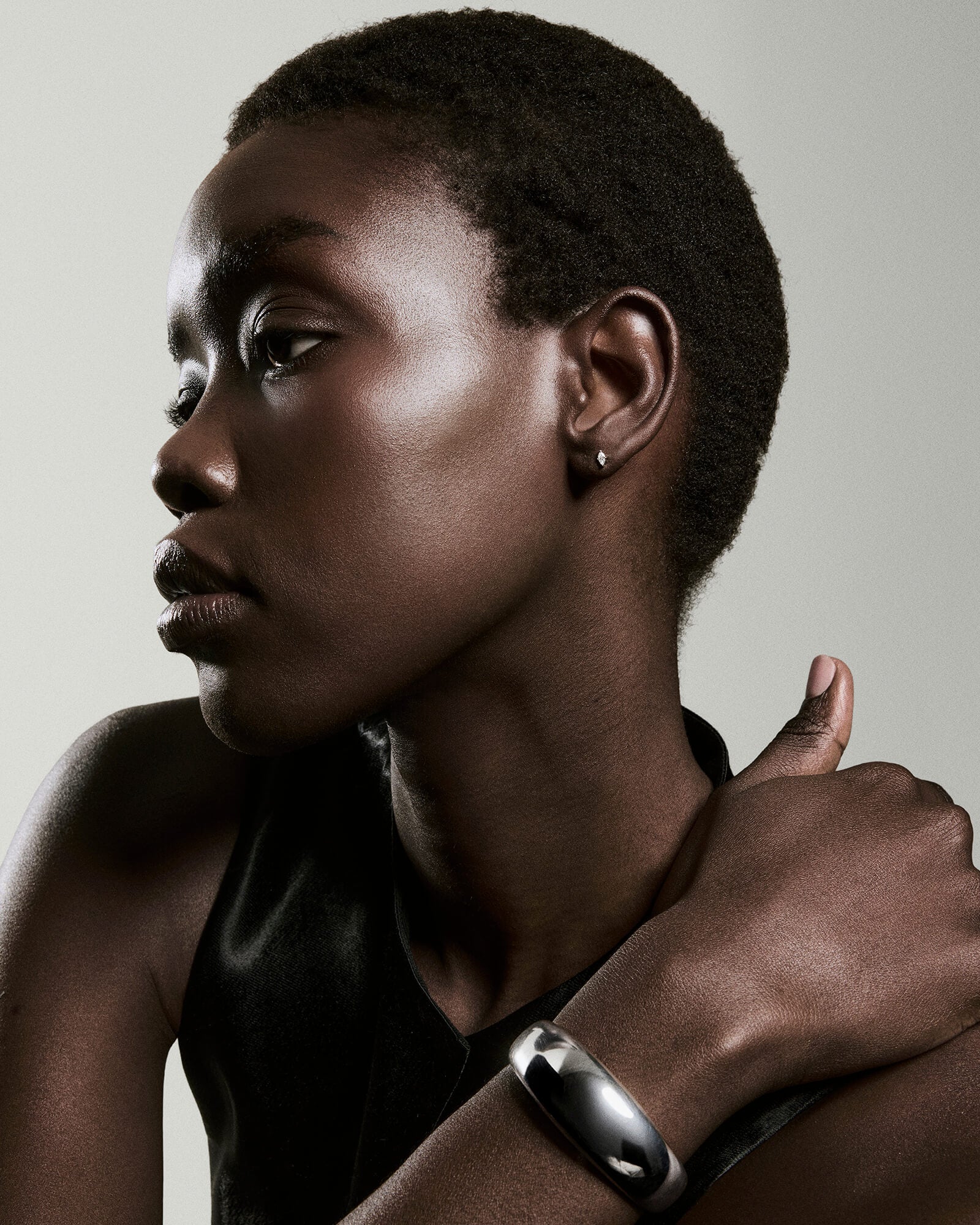Person wearing Piercing Studio - Lab Grown Diamond Marquise Studs, featuring a sleek, sharp design, paired with a metal cuff bracelet, in a contemplative pose.
