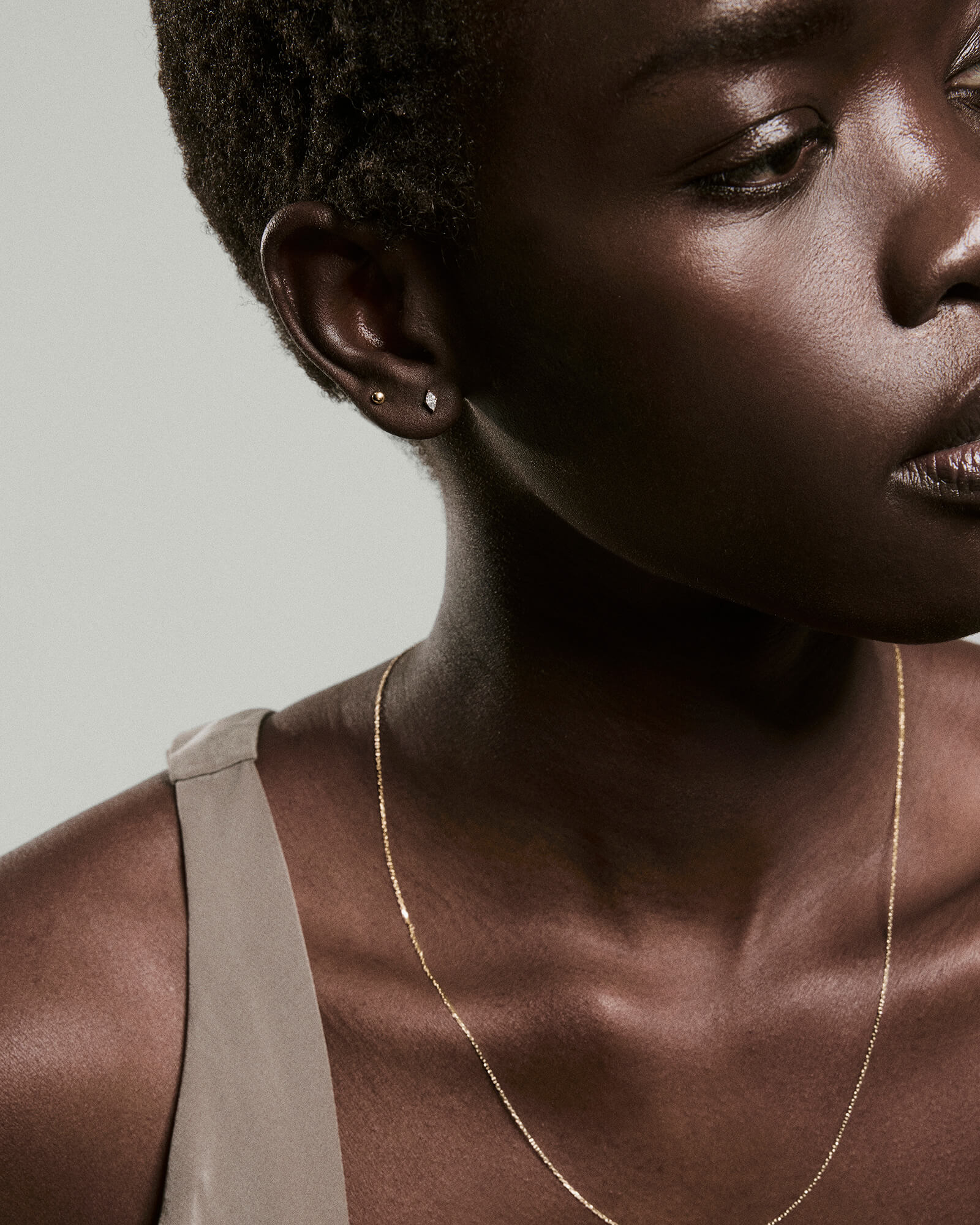 Close-up of a person wearing Piercing Studio's Lab Grown Diamond Marquise Studs, showcasing their elegant, sharp design alongside a delicate gold chain necklace.