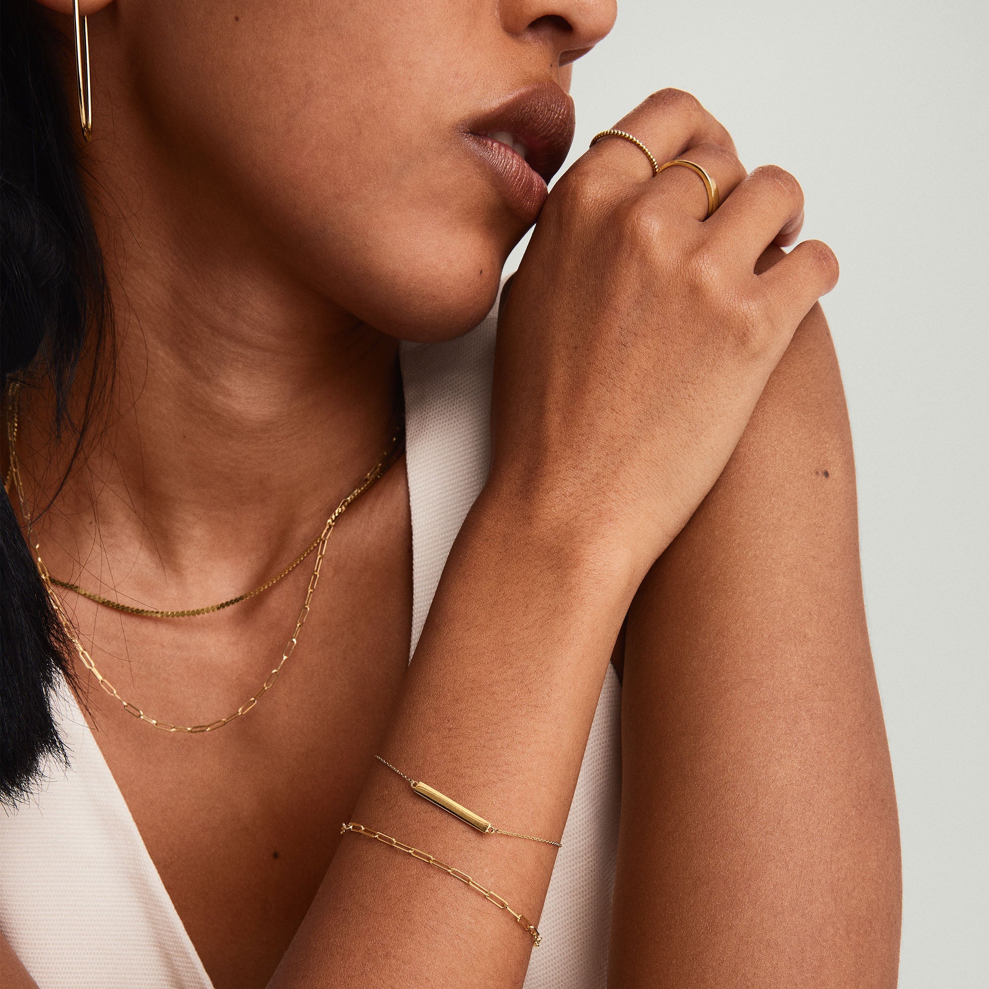 Close-up of a woman wearing a 14k gold Engravable Bar Bracelet on her wrist, showcasing its sleek, minimal design.