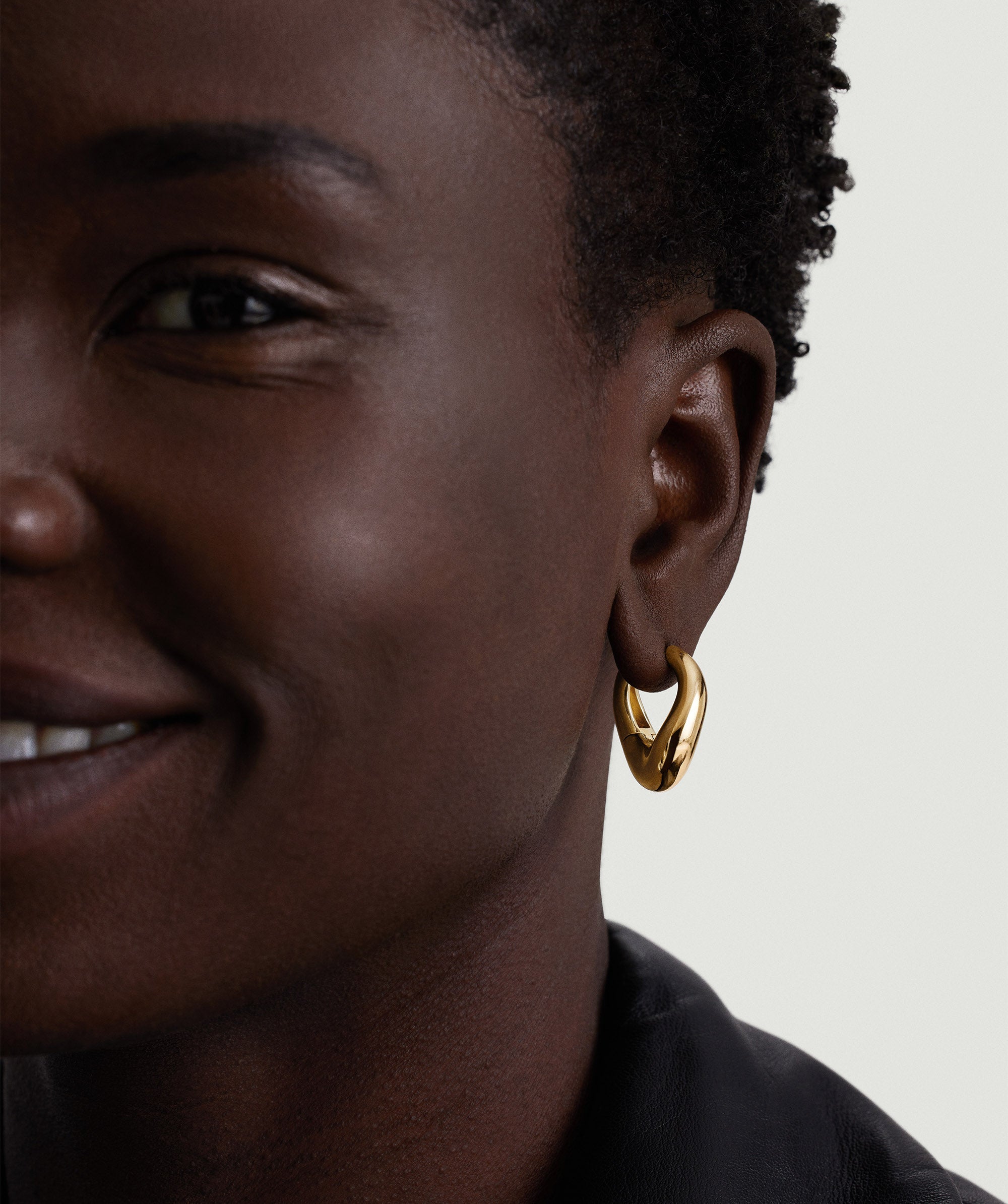 Close-up of a woman wearing the DÃ´me Figure Hoops, showcasing the sculptural 18k gold vermeil earrings that enhance her elegant look.