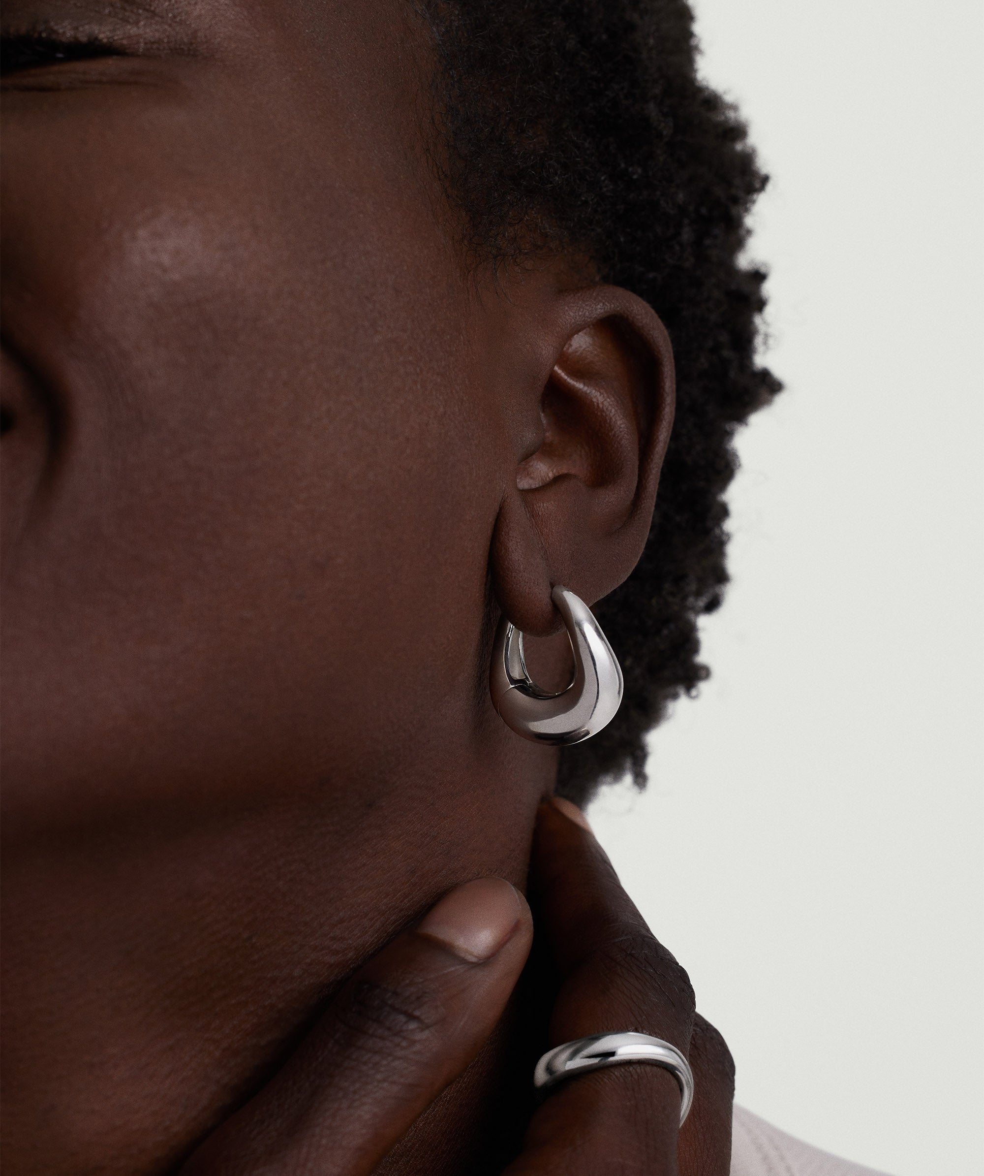 Figure Large Chunky Hoops: Close-up of a person wearing handcrafted sterling silver statement hoops, highlighting their sculptural design and artistic appeal.