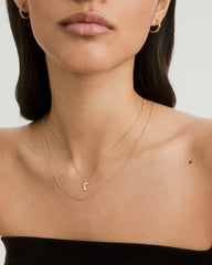 Close-up of a woman wearing a Gothic Letter Pendant necklace, showcasing its bold, edgy design as a striking fashion accessory.